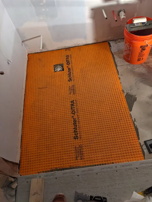 An orange sheet of plastic is being cemented to the floor