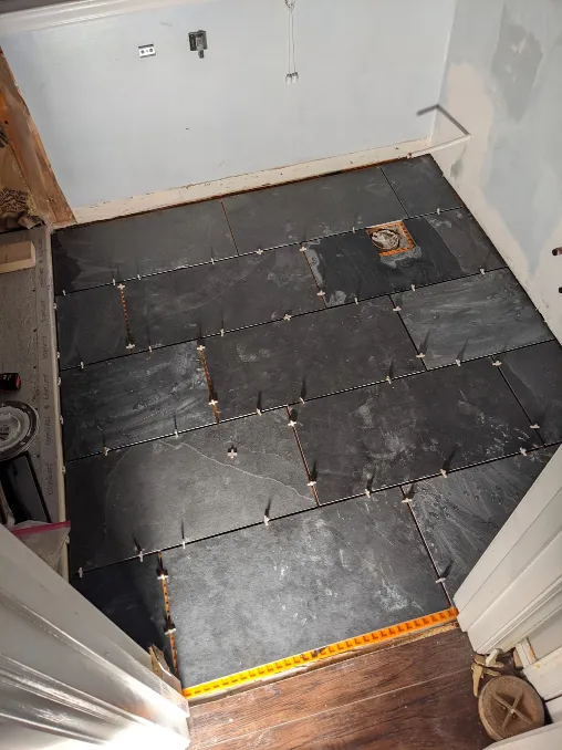 Tiles are arranged on the orange sheets from earlier. They have been cut to size