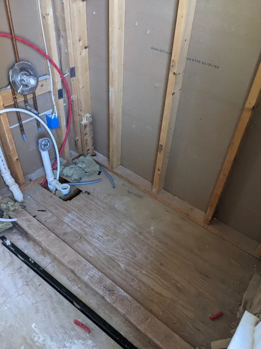 Pipes hang out of a wall, no sheetrock in sight