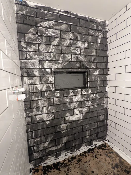 Black grout covers a wall. It is incredibly messy