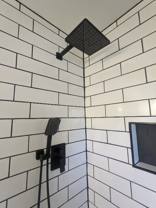 A fancy shower head and shower handle have been installed