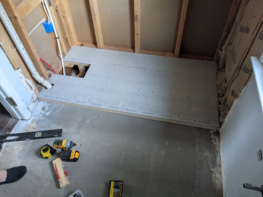 A sheet of cement board has been placed atop the wooden platform