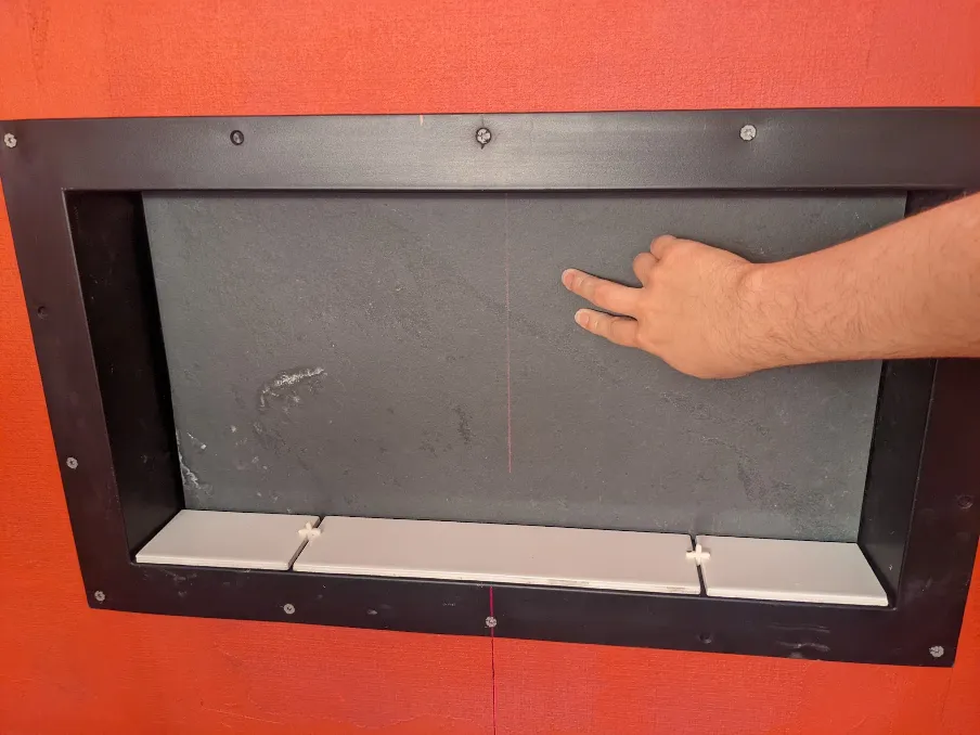 A slate tile is being held to the back of the plastic niche, and small subway tiles sit in front of it