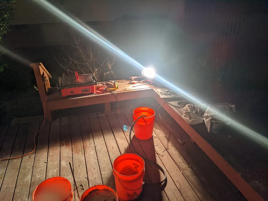 A tile saw sits on a deck in the dark, lit by a flood light. It looks very cold.
