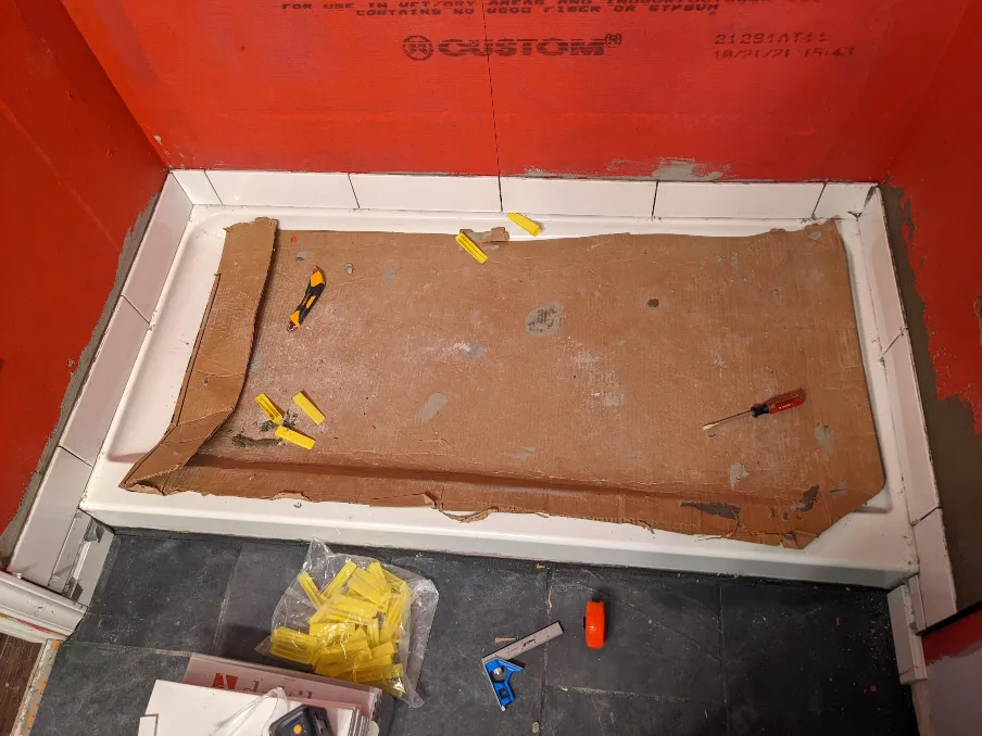 A single meticulously placed row of tiles is visible around the shower pan