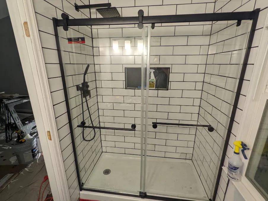 A shiny glass door hangs in front of the shower