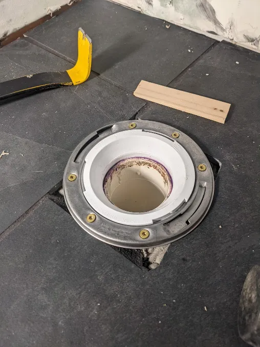 A new toilet flange is installed atop the tiles