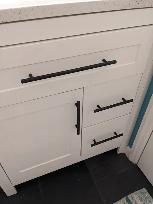 Fancy matte metal handles have been installed on the cabinets and drawers of the vanity